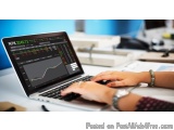 The image shows a person's hands typing on a laptop computer. The laptop is open and the screen is displaying a stock market...