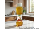 The image shows a bottle of honey on a kitchen countertop. The bottle is made of plastic and has a white cap. The label on th...