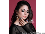 The image is a portrait of a young woman with long dark hair. She is wearing a black top with sheer sleeves and gold earrings...