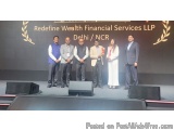The image shows a group of six people standing on a stage in front of a large banner that reads "Redefine Wealth Financial Se...