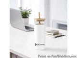 The image shows a white desk with a laptop and a small plant on it. On the desk, there is a white cylindrical container with...