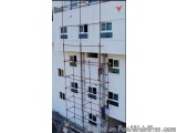 The image shows a tall white building with multiple windows and scaffolding on the side. The building appears to be a high-ri...