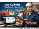 The image shows a man wearing a white hard hat and a blue shirt, holding a tablet and pointing at a laptop screen. He is stan...