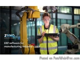 The image shows a young woman wearing a high visibility vest and safety goggles, standing in front of a large yellow robotic...