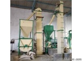 The image shows a large industrial machine inside a warehouse. The machine is made up of three tall, cylindrical structures w...