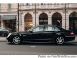 The image shows a black Mercedes-Benz S-Class car parked on the side of a street. The car is a luxury model with a sleek desi...