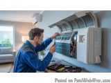 In this image, we can see a man working on an air conditioning unit. He is wearing a blue uniform and is holding a tool in hi...