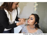 The image shows a young woman getting her makeup done by a makeup artist. The makeup artist is applying blue eyeshadow to the...
