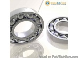 The image shows two spherical bearings, one on the left and one in the right. The bearings are made of metal and have a shiny...