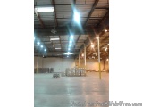 The image shows the interior of a large warehouse or storage facility. The floor is made of concrete and the walls are painte...