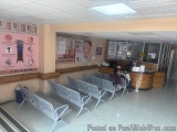The image shows the interior of a waiting area in a hospital. The floor is made of white tiles and there are several rows of...