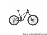 The image is of a mountain bike. The bike is brown in color with blue accents on the frame and seat. It has a full suspension...