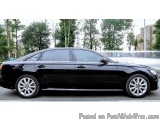 The image shows a black car parked on the side of a road. The car appears to be a luxury sedan with a sleek design and chrome...