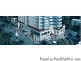 The image is an aerial view of a modern building with a high-rise facade. The building is surrounded by palm trees and other...