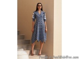 The image shows a young woman standing on a set of stairs. She is wearing a blue and white plaid dress with a collared neckli...