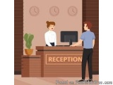 The image shows a reception desk in a hotel lobby. There are two people standing behind the desk, one is a receptionist and t...
