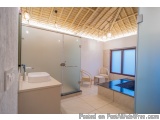 The image shows a modern bathroom with a wooden ceiling and white walls. The floor is made of light-colored tiles and the wal...