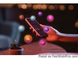 The image shows a hand holding a smartphone with a colorful app open on the screen. The app appears to be a social media plat...