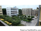 The image shows a view of a residential area from a high-rise building. The building is white with multiple floors and balcon...
