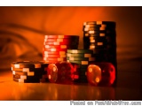 The image shows a stack of poker chips and two red dices on a wooden surface. The chips are of different colors - red, green,...