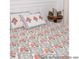 The image shows a bed with a white headboard and a gray and white quilt on it. The quilt is made up of a repeating pattern of...