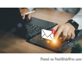 The image shows a person's hand on a laptop keyboard, typing on a tablet. The tablet is placed on a wooden desk, and the pers...