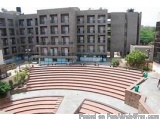 The image shows an aerial view of a large, modern apartment building with multiple floors and balconies. The building appears...