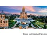 The image is a beautiful landscape photograph of a large church with a golden dome on top. The church is located in a park-li...
