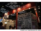 The image shows a booth at a book fair or exhibition. The booth has a red and white sign that reads "DOUBLE9 BOOKS" with the...