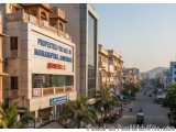The image shows a busy street in a city with tall buildings on both sides. The buildings are located on a hillside and the sk...