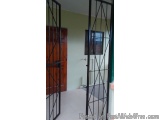 The image shows a pair of black metal gates in a room with a wooden door in the background. The gates are made of metal and h...