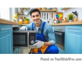 In this image, we can see a young man in a blue overalls and white gloves holding a microwave oven in a kitchen. He is smilin...