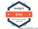 The image is a logo for HubSpot Elite Solutions Partner Program. The logo is in the shape of a hexagon with a blue and orange...