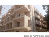 The image shows a tall, multi-storey building with a beige exterior. The building appears to be made of concrete and has mult...