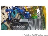 The image shows a close-up of a blue and yellow machine with a long arm and a handle. The machine appears to be a conveyor be...
