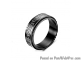 The image is of a black ring with a Greek key design on it. The ring appears to be made of a shiny, matte material and has a...