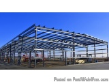The image shows a large industrial structure made of steel beams and corrugated metal. The structure is located in an open ar...