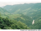 The image shows a beautiful landscape of a mountainous area. The mountains are covered in green trees and shrubs, and the val...