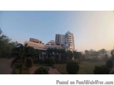 The image shows a large, modern building with multiple floors and balconies. The building appears to be a hotel or a resident...