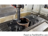 The image shows a close-up of a CNC milling machine in action. The machine is mounted on a metal workbench with a circular ba...
