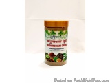 The image is of a jar of Madhunashaka Churna, a traditional Indian spice. The jar is made of glass and has a brown lid. The l...