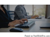The image shows a person's hands typing on a computer keyboard. The person is sitting at a desk with a computer monitor and a...