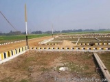 The image shows a construction site with a large field in the background. The field is surrounded by a fence with yellow and...
