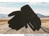 The image shows a pair of black gloves resting on the side of a road. The gloves appear to be made of a soft, textured materi...