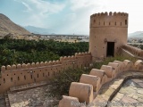The image shows a round tower with a pointed top and a small entrance in the center. The tower is made of light-colored stone...