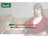 The image shows a young woman sitting in a hospital bed with a bandage wrapped around her head. She is wearing a red cardigan...