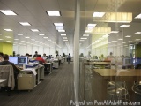 The image shows an office space with multiple desks and chairs arranged in rows. The desks are arranged in a neat and orderly...