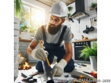 In this image, we can see a man wearing a white hard hat and overalls, kneeling on the floor in a kitchen. He is holding a pe...