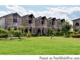 The image shows a large, multi-story building with a green lawn in front of it. The building appears to be a residential comp...