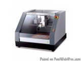 The image shows a Roland MIX-40A 3D printer. It is a large, rectangular machine with a grey body and a black base. The top of...